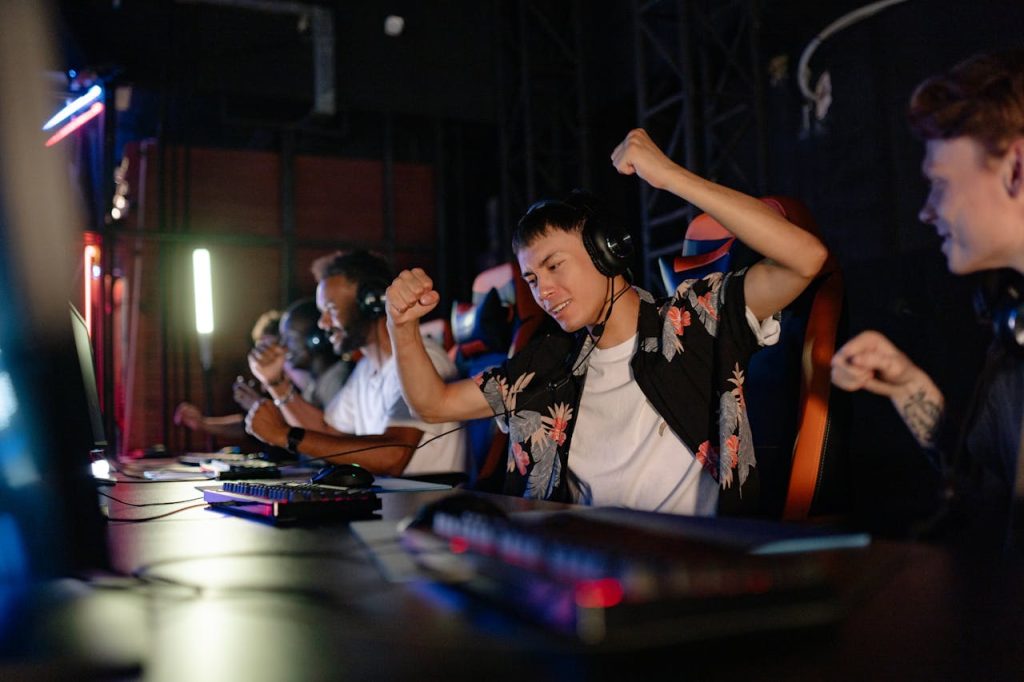 Excited gamers celebrating a win in a competitive gaming tournament with headphones.